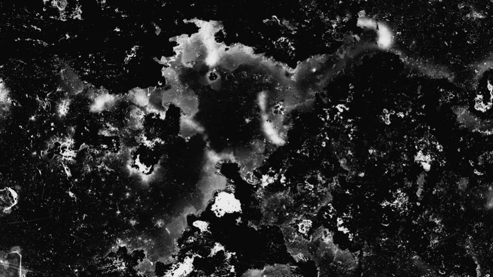 Kameralöst fotografi av ett kalhygge. En svart bild med vita abstrakta fläckar.