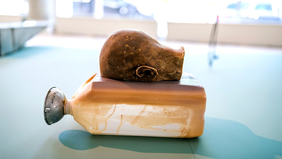 Foto på ett skulpterat huvud i bivax, som ligger i en plastdunk.